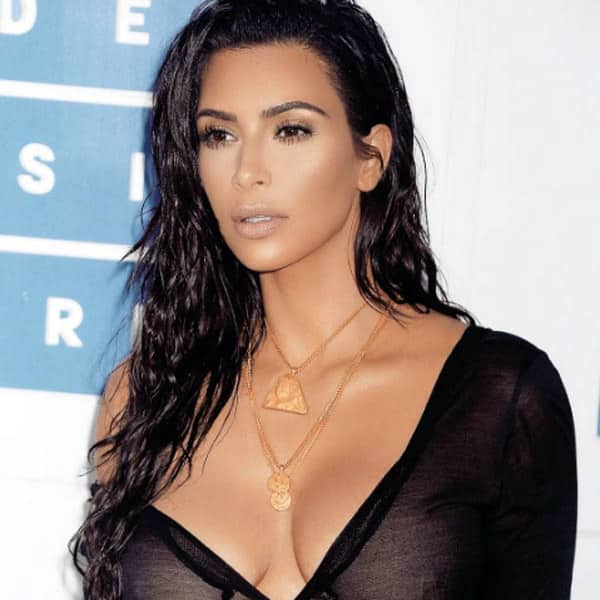 Kim wears a see through black one shoulder dress and looks absolutely flawless with the slightly bronzed make up and beach waves.